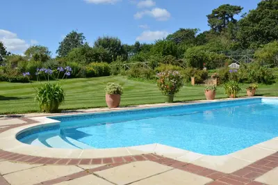 a swimming pool in a yard with potted plants at Stable Cottage at the Grove, Great Glemham in Framlingham
