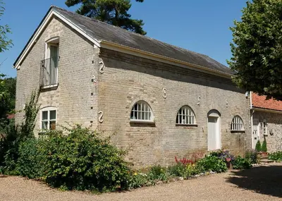 an old brick building with windows and a roof at Stable Cottage at the Grove, Great Glemham in Framlingham