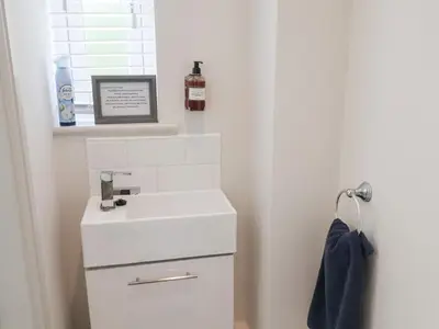 a white bathroom with a sink and a mirror at 1 Coconut Cottage, Long Melford in Long Melford