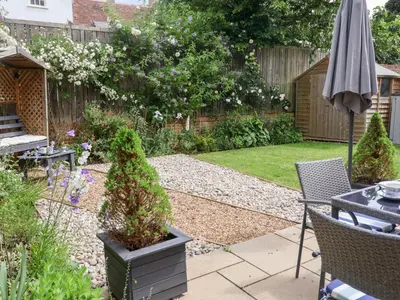 a garden with an umbrella and a table and chairs at 1 Coconut Cottage, Long Melford in Long Melford
