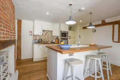 a kitchen with white cabinets and bar stools at Beresford House in Woodbridge