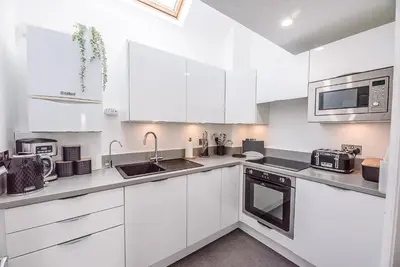 a white kitchen with white cabinets and appliances at Coasters, Aldeburgh in Aldeburgh