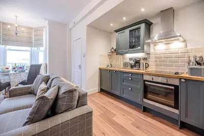 a living room with a couch and a kitchen at The Apartment at Clare House, Aldeburgh in Aldeburgh
