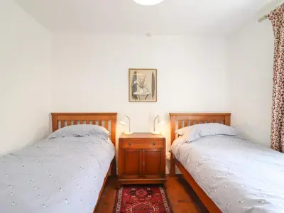 a bedroom with two twin beds and a night stand at Warren Cottage in Leavenheath
