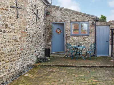 a brick building with a blue door and a table at The Old Butcher's Shop in Wereham