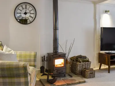 a living room with a stove with a clock on the wall at The Old Butcher's Shop in Wereham