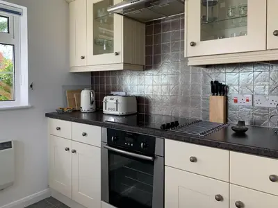 a kitchen with white cabinets and black counter tops at Quayside Cottage Uk33899 in Waldringfield