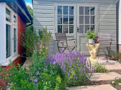 a patio with two chairs and flowers in front of a house at The Boathouse Uk33900 in Waldringfield