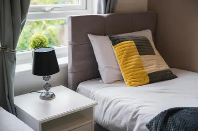 a bed with a yellow pillow next to a window at Summer Deal 20 PRC OFF 4BR 2BATH Families Groups By Trinity Stays Short Lets & Serviced Accommodation Cambridge in Cambridge
