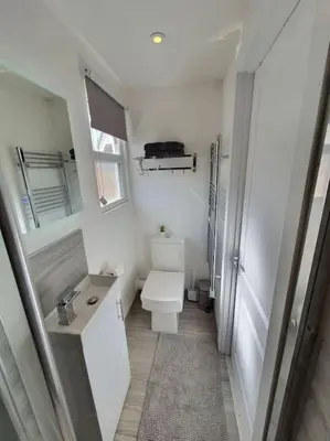 a white bathroom with a toilet and a sink at The Tiny Sea Gem in Jaywick Sands