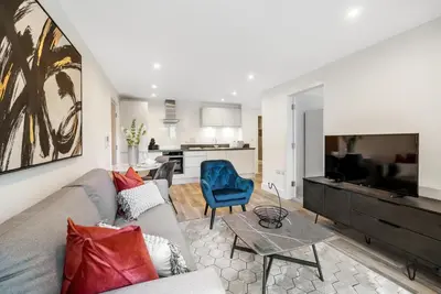 a living room with a gray couch and a blue chair at Tailored Stays - Water Street Apartments in Cambridge