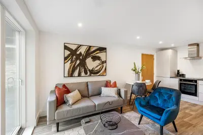 a living room with a couch and a blue chair at Tailored Stays - Water Street Apartments in Cambridge