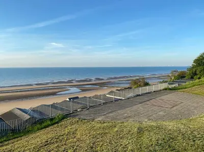a beach with a fence next to the ocean at Lovely 1 bed flat 200 metres from beach in Walton-on-the-Naze