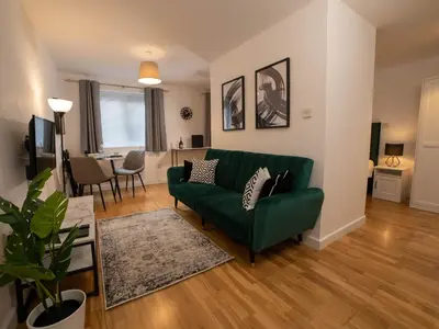 a living room with a green couch and a table at Modern & Central - KING Bed, Super FAST Wi-Fi in Cambridge