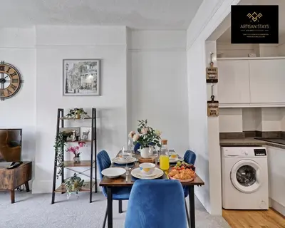 a dining room with a table and blue chairs at Deluxe Apartment in Southend-On-Sea by Artisan Stays I Free Parking I Sleeps 4 in Southend-on-Sea