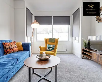 a living room with a blue couch and a table at Deluxe Apartment in Southend-On-Sea by Artisan Stays I Free Parking I Sleeps 4 in Southend-on-Sea