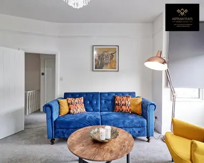 a living room with a blue couch and a table at Deluxe Apartment in Southend-On-Sea by Artisan Stays I Free Parking I Sleeps 4 in Southend-on-Sea