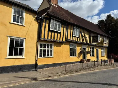 a yellow building with white windows on a street at The Crown, Bildeston in Bildeston