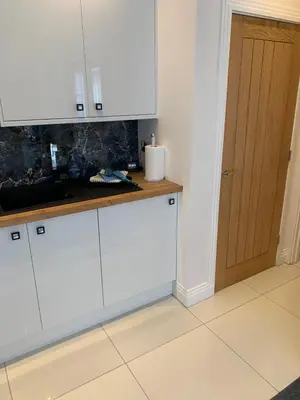 a kitchen with white cabinets and a wooden door at The office at the old Forge in Great Wymondley