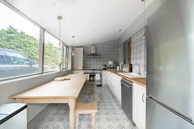 a kitchen with white cabinets and a wooden counter top at Suitable For Contractors 2 Double Beds and Sofa Bed Private Parking in Harlow