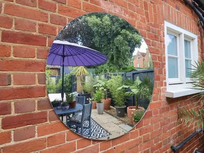 a mirror on the side of a brick building with an umbrella at Tower End Cottage in Woodbridge