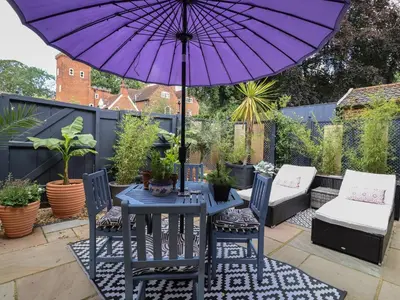 a purple umbrella on a patio with a table and chairs at Tower End Cottage in Woodbridge