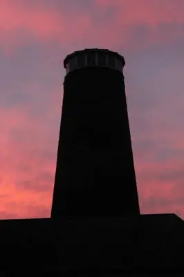 a lighthouse on top of a building with a sunset at The Old Mill, 7 storey,, dog friendly outdoor pool & bbq in Stoke Ferry
