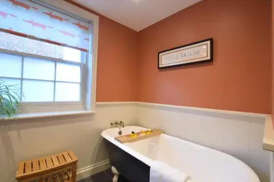 a bathtub in a bathroom with orange walls and a window at 11 Crabbe Street, Aldeburgh in Aldeburgh