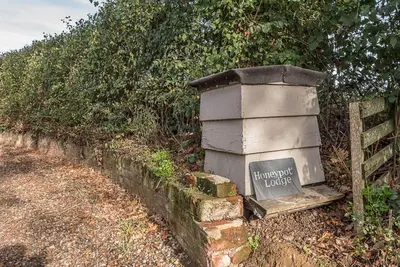 a sign on a brick wall next to a fence at Little Honey Pot, Benhall in Saxmundham