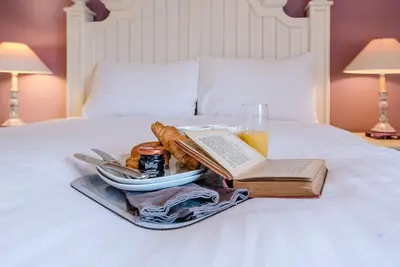 a tray of food and a book on a bed at 4 Ropers Court, Lavenham in Lavenham
