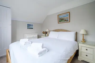 a bedroom with a white bed with towels on it at 9 Whinlands in Thorpeness