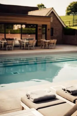 a swimming pool with two lounge chairs in front of a house at Talbooth House & Spa in Dedham