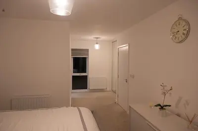 a bedroom with a bed and a clock on the wall at Exquisite cozy house, close to Train Station and amenities in Harold Wood