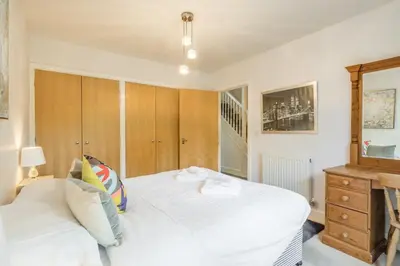 a bedroom with a white bed and a wooden cabinet at Charming & Spacious House With FREE PARKING in Chesterton