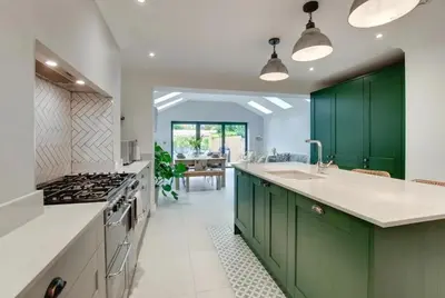 a kitchen with green cabinets and a sink and a stove at Belle Vue Cottage in Downham Market