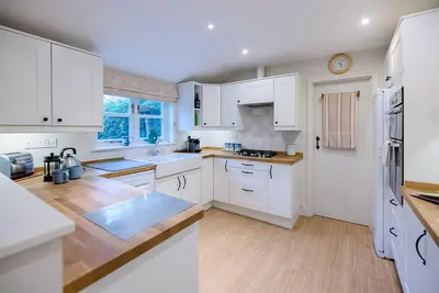 a white kitchen with white cabinets and wooden floors at 18 Hartington, Aldeburgh in Aldeburgh