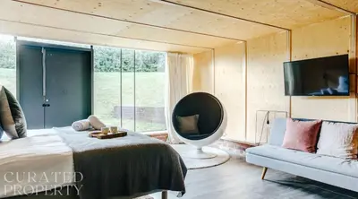 a bedroom with a bed and a mirror and a couch at Grand Suffolk Barn Conversion in Chelsworth