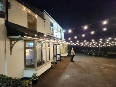 a man standing outside of a building with lights at The Swan - A Colombo Edition Hotel in Ely