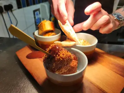 a person eating food in bowls on a table at The Swan - A Colombo Edition Hotel in Ely