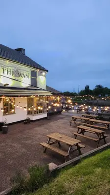 a group of picnic tables in front of a building at The Swan - A Colombo Edition Hotel in Ely