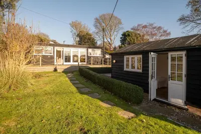 a small black house with a porch and a yard at 9 Uplands in Thorpeness