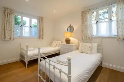 a bedroom with two beds and two windows at 9 Uplands in Thorpeness