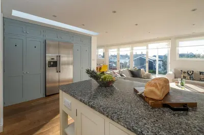 a kitchen with a counter top and a living room at 9 Uplands in Thorpeness