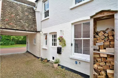 a house with a pile of wood next to a garage at Cosy Courtyard Cottage sleeps 4 with Log Burner, close to Cambridge in Cambridge