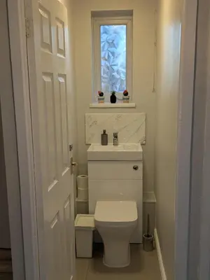 a bathroom with a toilet and a sink and a window at A&A Apartment Basildon in Nevendon