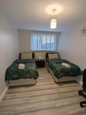 a bedroom with two beds and a window at A&A Apartment Basildon in Nevendon