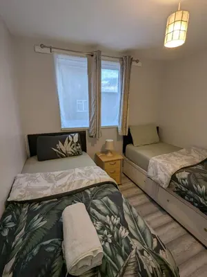 a bedroom with two beds and a window at A&A Apartment Basildon in Nevendon