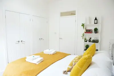 a white bedroom with a bed with a yellow blanket at King's - Spacious Central Ground Floor Apartment in Cambridge