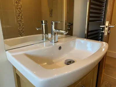 a white sink in a bathroom with a mirror at Lynford Holiday Cottages nestled in the heart of Thetford Forest in Mundford