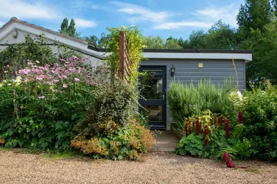 a garden with flowers and a garage at The Garden Cottage, Wenhaston, Suffolk, near coast in Halesworth